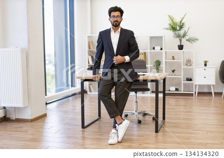 A well-dressed businessman poses confidently in a contemporary office setting, exuding professionalism and success A well-dressed businessman poses confidently in a contemporary office setting, exuding professionalism and success 134134320