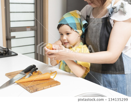 Mother and son peeling carrots together in the kitchen 134135299