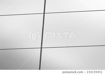 Flat design glass curtain wall facade is featuring reflective panels and dark metal mullion grid Flat design glass curtain wall facade is featuring reflective panels and dark metal mullion grid 134135451