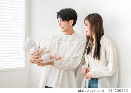 A young couple cradling their baby in the living room and dining room 134136333