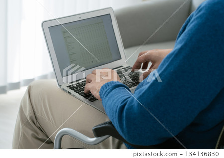 坐在輪椅上的男子正在使用筆記型電腦 134136830