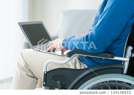 Man in a wheelchair using a laptop Man in a wheelchair using a laptop 134136833