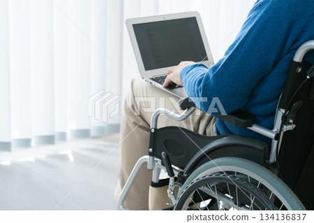坐在輪椅上的男子正在使用筆記型電腦 坐在輪椅上的男子正在使用筆記型電腦 134136837