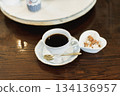 木桌上放著一杯咖啡和一個白色盤子。 134136957
