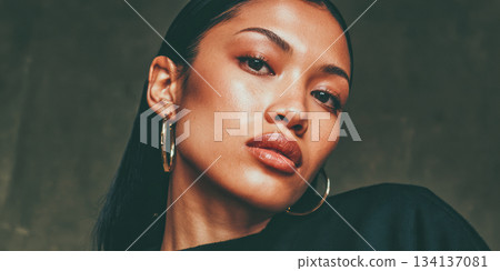Portrait of a model posing confidently with a serious expression in a dimly lit studio setting 134137081