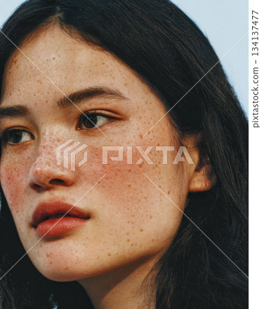 Portrait of a young woman with freckles against a clear sky during daytime 134137477