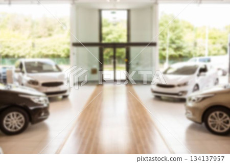 Walkway is leading toward glass doors in flat design showroom, sedans on tiled floor, with greenery 134137957