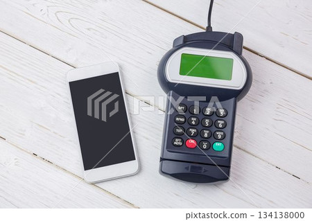 Smartphone and card terminal with keypad are sitting on white tabletop with cable, flat design Smartphone and card terminal with keypad are sitting on white tabletop with cable, flat design 134138000