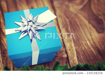 Flat-design blue gift box featuring white ribbon, silver bow is sitting on table, with pine branch Flat-design blue gift box featuring white ribbon, silver bow is sitting on table, with pine branch 134138258