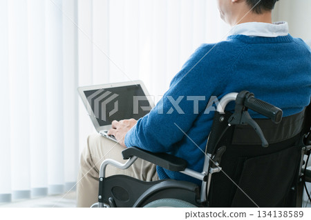 坐在輪椅上的男子正在使用筆記型電腦 134138589