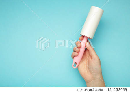 Woman holding lint roller on blue background. Top view Woman holding lint roller on blue background. Top view 134138669