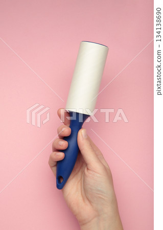 Woman holding lint roller on pink background. Top view Woman holding lint roller on pink background. Top view 134138690