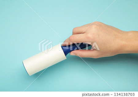 Woman holding lint roller on blue background. Top view Woman holding lint roller on blue background. Top view 134138703