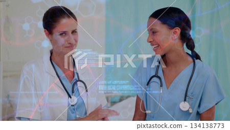 Analyzing two doctors wearing scrubs and lab coat examining DNA graphics in exam room, stethoscopes Analyzing two doctors wearing scrubs and lab coat examining DNA graphics in exam room, stethoscopes 134138773