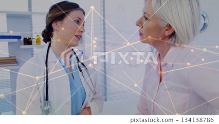 Consulting doctor discussing health with patient in consultation room, with stethoscope and shelves Consulting doctor discussing health with patient in consultation room, with stethoscope and shelves 134138786