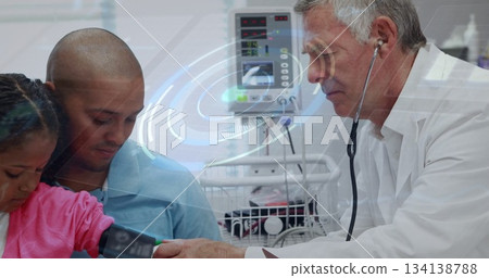 Doctor in white coat measuring girl's blood pressure at hospital ward, digital monitor, copy space 134138788