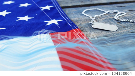 Showing silver dog tags resting on rustic wooden tabletop, with American flag draping, copy space Showing silver dog tags resting on rustic wooden tabletop, with American flag draping, copy space 134138904