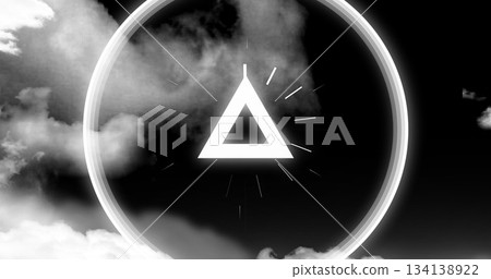 Floating equilateral triangle casting glow amid swirling clouds, with halo radiating light rays 134138922