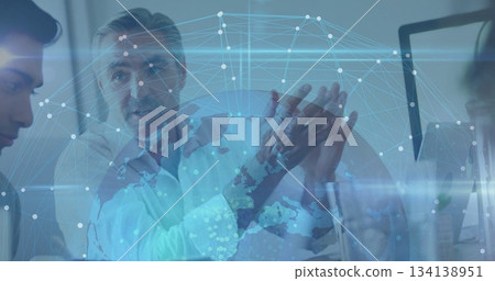 Gesturing manager in shirt speaking with colleagues in meeting room at desk, network map overlay Gesturing manager in shirt speaking with colleagues in meeting room at desk, network map overlay 134138951
