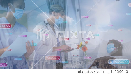 Writing doctor in lab coat documenting medical charts on clipboard at bedside with digital overlays 134139040