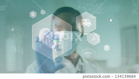 Woman in lab coat mask gloves examining vial in lab corridor, with stethoscope and icons 134139084