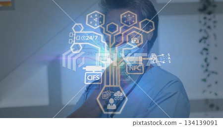 Holding stethoscope doctor wearing blue scrubs and mask in clinic, viewing holographic interface Holding stethoscope doctor wearing blue scrubs and mask in clinic, viewing holographic interface 134139091