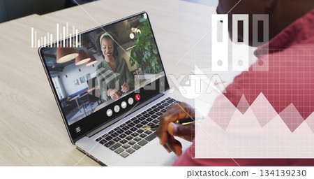 Holding pen senior man viewing headset-wearing woman on laptop in office, with chart icons 134139230