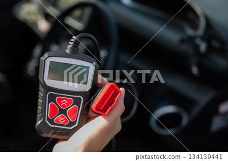 Woman using OBD2 diagnostic scanner. Woman using OBD2 diagnostic scanner. 134139441