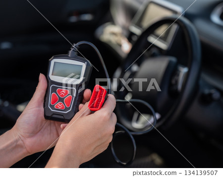 Woman using OBD2 diagnostic scanner. Woman using OBD2 diagnostic scanner. 134139507