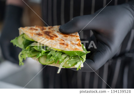 Chef holding a flatbread with herbs. Chef holding a flatbread with herbs. 134139528