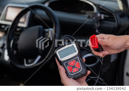 Woman using OBD2 diagnostic scanner. Woman using OBD2 diagnostic scanner. 134139542