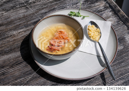 Chicken broth with noodles on a wooden table. Chicken broth with noodles on a wooden table. 134139626