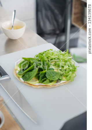 The chef prepares a flatbread with herbs. The chef prepares a flatbread with herbs. 134139678