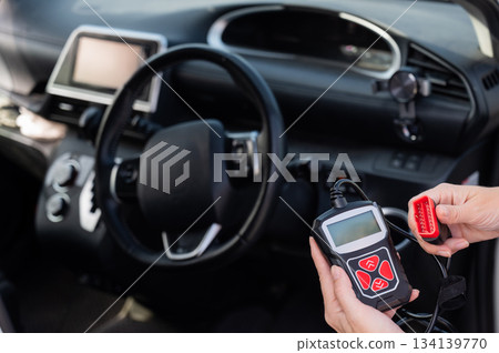 Woman using OBD2 diagnostic scanner. Woman using OBD2 diagnostic scanner. 134139770