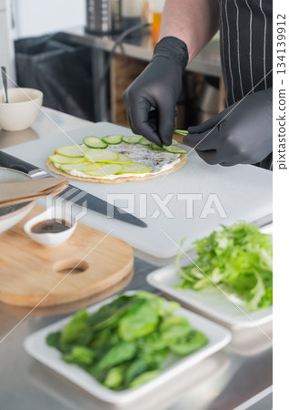 The chef prepares a flatbread with herbs. The chef prepares a flatbread with herbs. 134139912