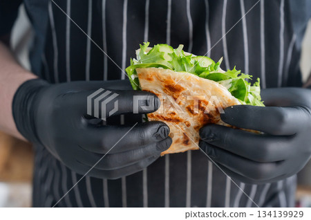 Chef holding a flatbread with herbs.  134139929