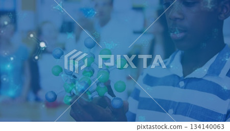 Exploring molecular model with green-gray atoms and rods boy in polo shirt in classroom, copy space Exploring molecular model with green-gray atoms and rods boy in polo shirt in classroom, copy space 134140063