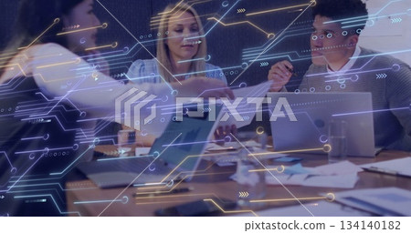 Professionals in office attire collaborating over devices and charts at office table, tech overlay 134140182