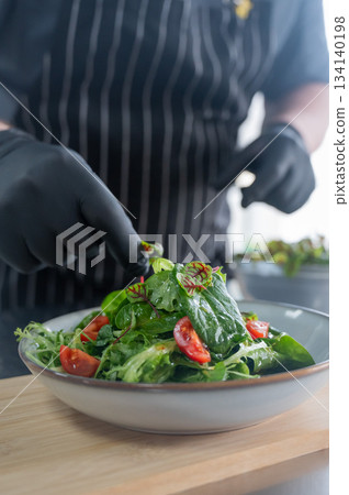 The chef prepares a salad.  134140198