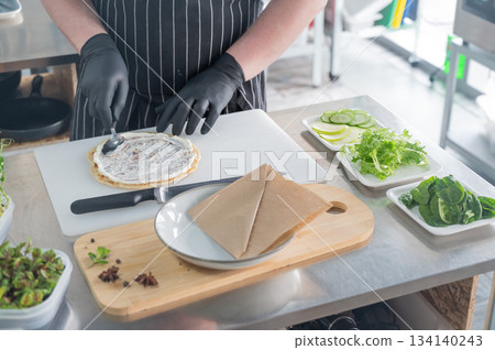 The chef prepares a flatbread with herbs. The chef prepares a flatbread with herbs. 134140243