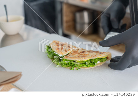 The chef prepares a flatbread with herbs.  134140259