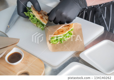 The chef prepares a flatbread with herbs. The chef prepares a flatbread with herbs. 134140262