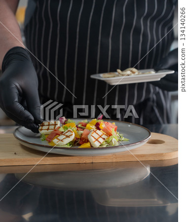 The chef lays out the salad.  134140266