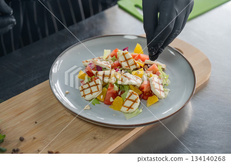 The chef seasons the salad with sauce. The chef seasons the salad with sauce. 134140268