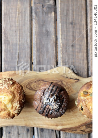 Three types of muffins arranged on a wooden board Three types of muffins arranged on a wooden board 134140302