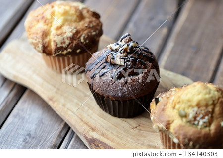 Three types of muffins arranged on a wooden board Three types of muffins arranged on a wooden board 134140303