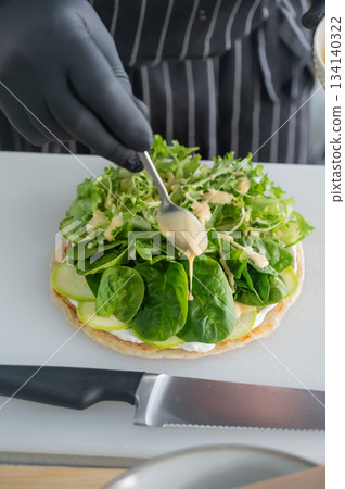 The chef prepares a flatbread with herbs. The chef prepares a flatbread with herbs. 134140322