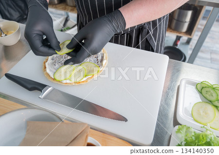 The chef prepares a flatbread with herbs.  134140350
