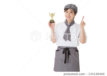 一位身穿廚師服的女子手捧獎杯 一位身穿廚師服的女子手捧獎杯 134140440