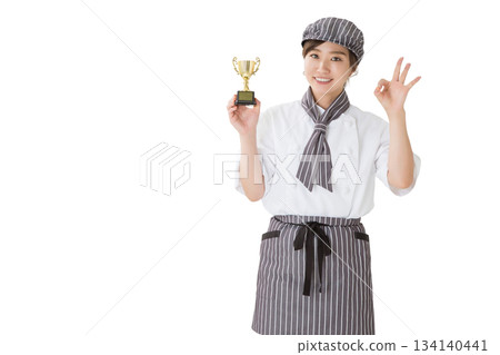 一位身穿廚師服的女子手捧獎杯 一位身穿廚師服的女子手捧獎杯 134140441